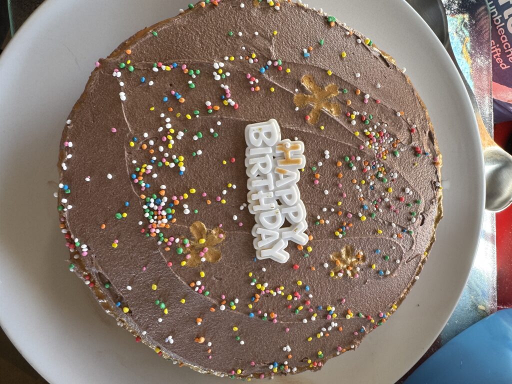 Chocolate cake with sprinkles and the words Happy Birthday.